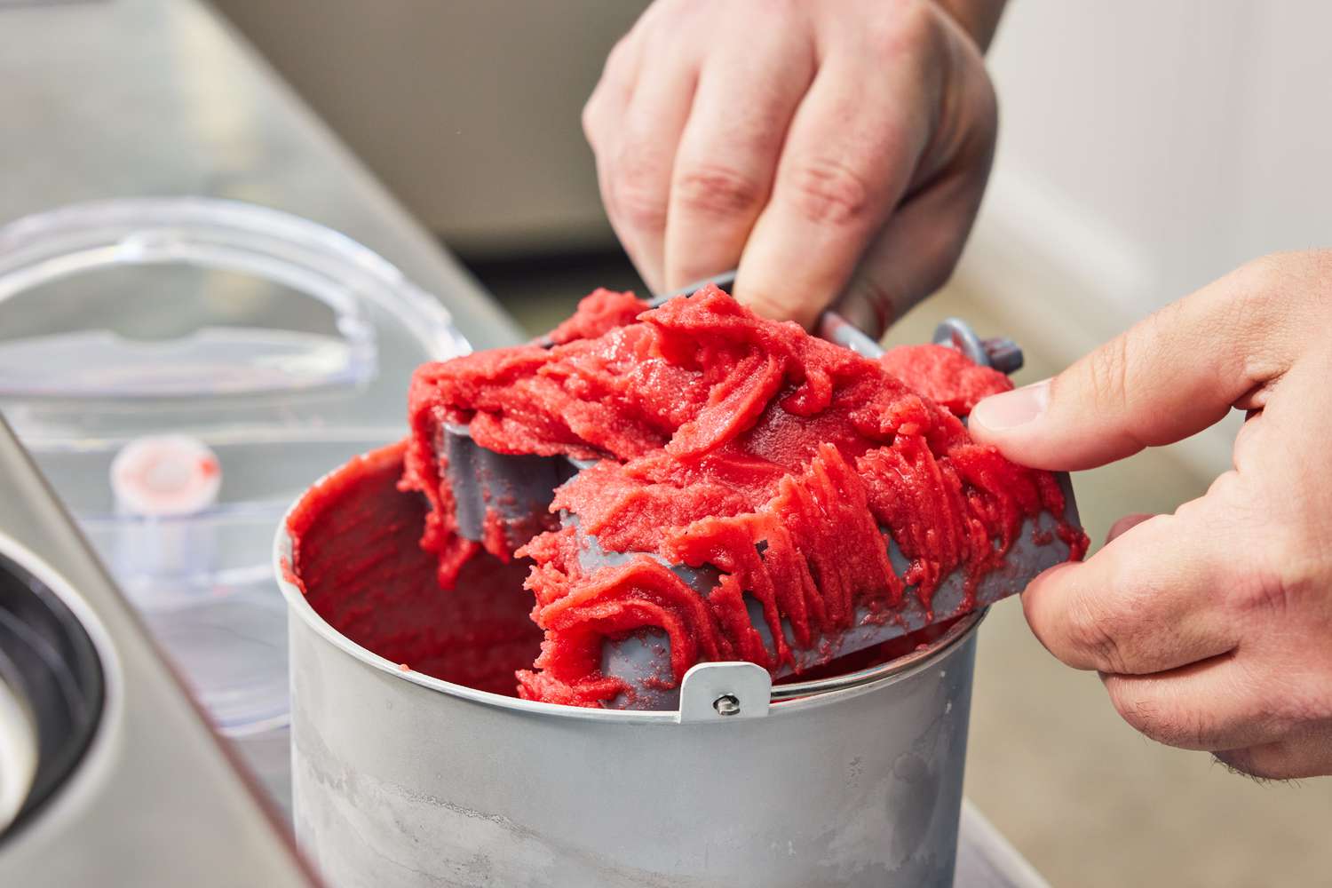 Person scraping sorbet from paddle of Cuisinart ICE-100 Compressor Ice Cream and Gelato Maker