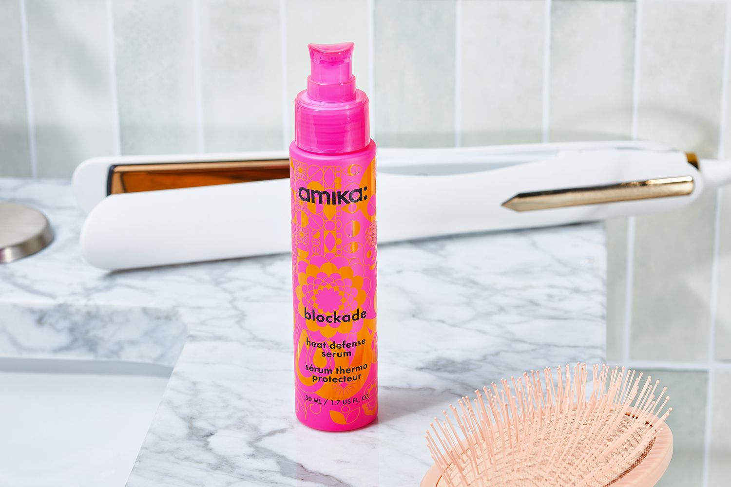 Amika Blockade Heat Defense Serum bottle sits on bathroom counter with hair styling tools