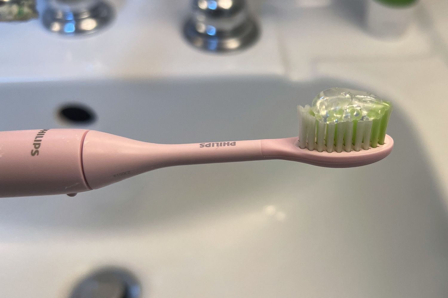 A dot of TheraBreath Fresh Breath Toothpaste on a toothbrush with a blurry sink in the background