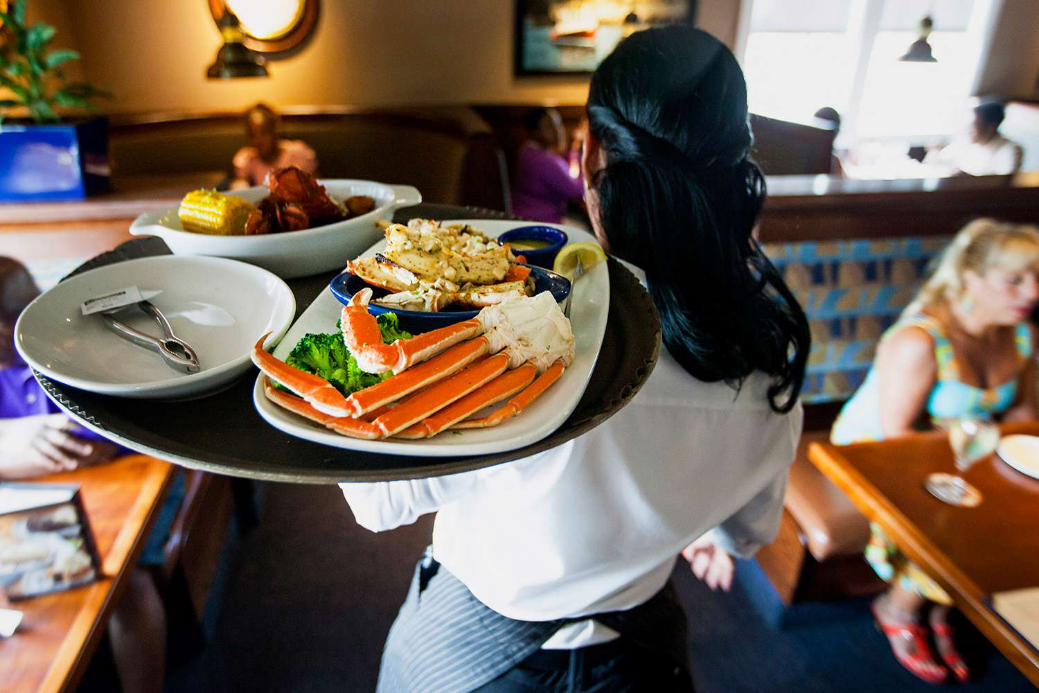 A waitress carries a tray a lobster kettle and a crab trio dish at a Red Lobster restaurant