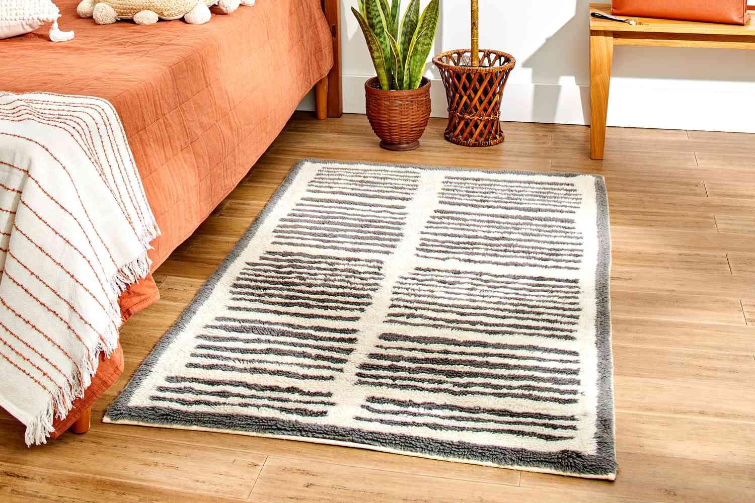 The AllModern Machine Washable Hand-Woven Wool Ivory/Charcoal Area Rug in a bedroom setting