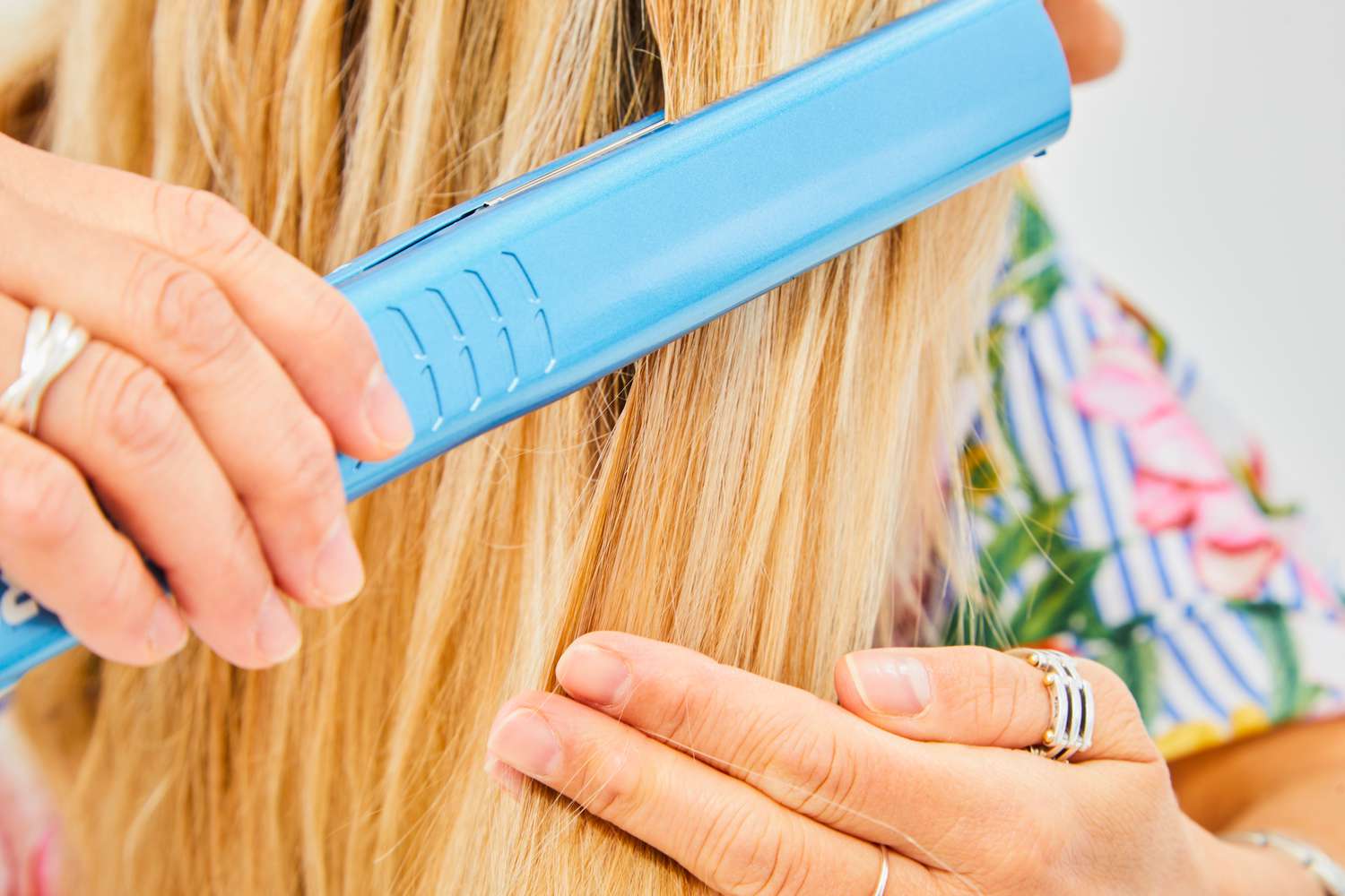 person uses flat iron on hair with Living Proof Restore Perfecting Spray