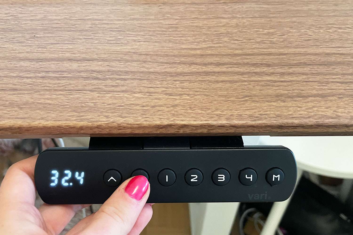 Person using the buttons on the Vari Essential Electric Standing Desk to adjust the height