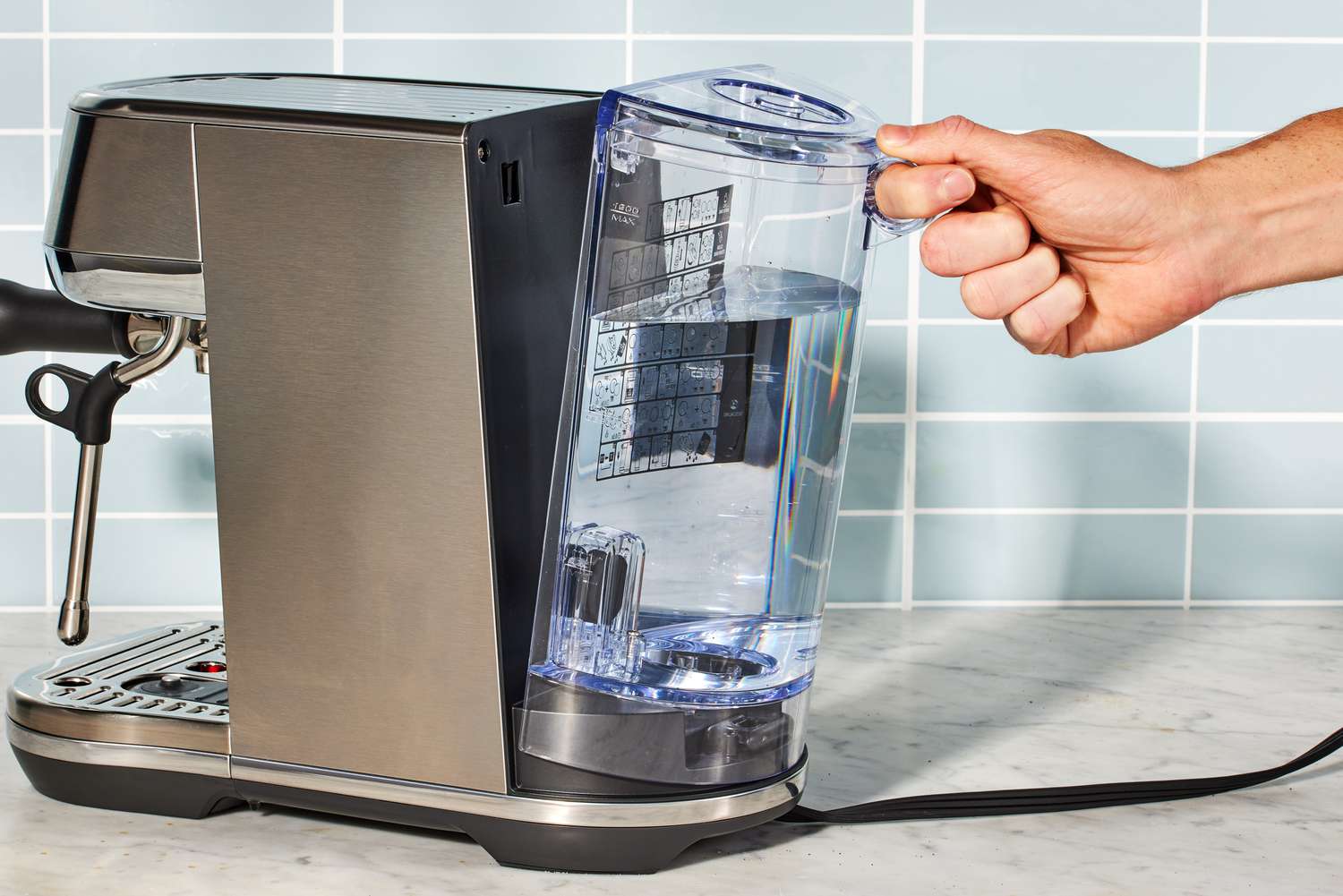 A hand removing the water tank of the Breville Bambino Plus Espresso Machine.