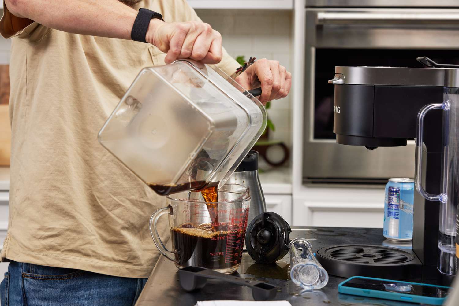 Person pouring coffee into a measuring cup from a Keurig K-Duo Plus Coffee Maker, Single Serve and 12-Cup Carafe Drip Coffee Brewer