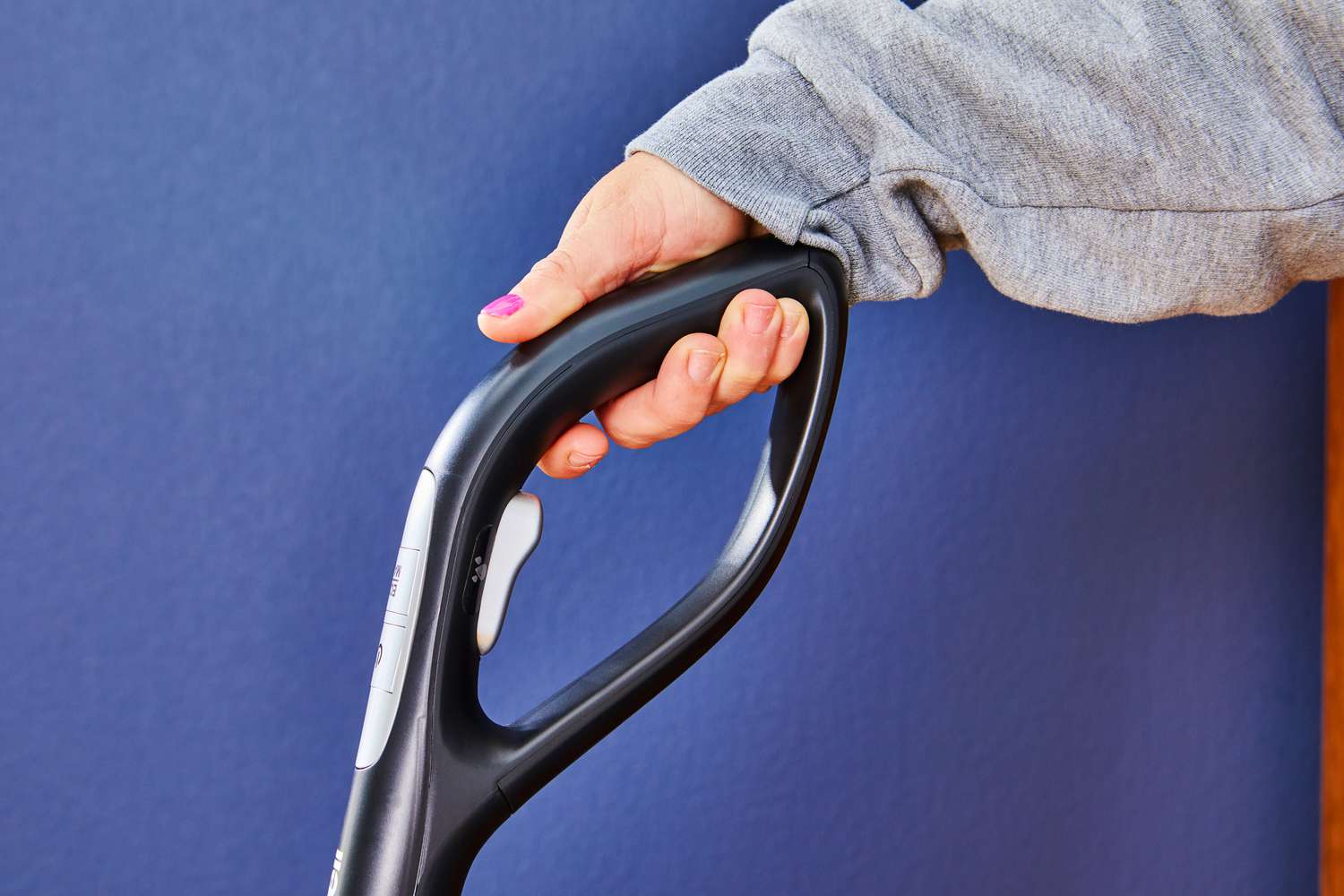 A close-up of a hand holding the handle of the Ecowell LULU Quick Clean P05 Cordless Multi-Surface Wet Dry Vacuum