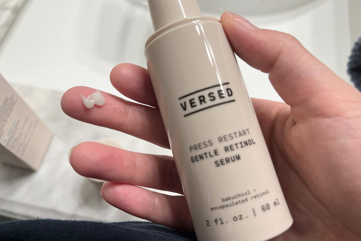 A bottle of the Versed Gentle Retinol Serum with small amount of product on a finger
