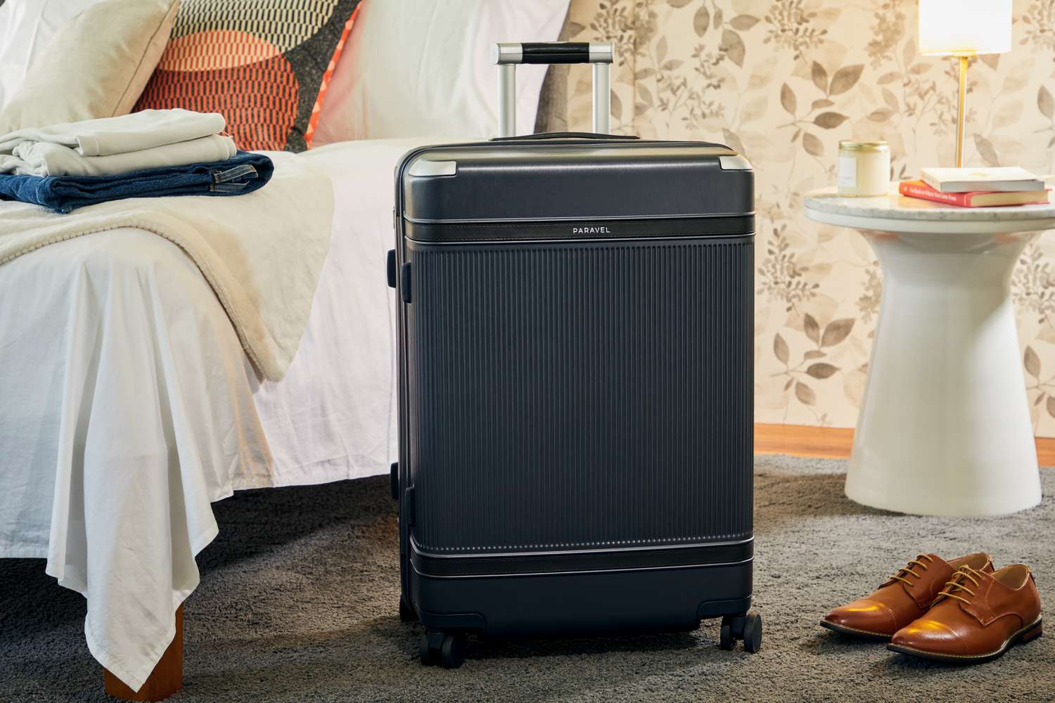 Paravel Aviator Grand Checked Luggage displayed in a room next to a bed and a white bedside table