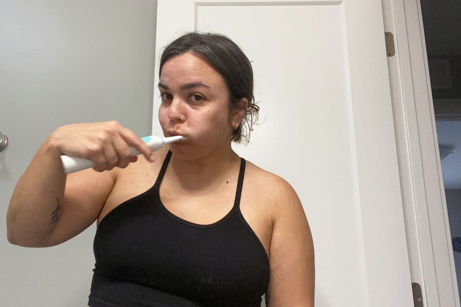 A person standing in front of a door brushing their teeth with Simplut Chewable Toothpaste Tablets with Fluoride