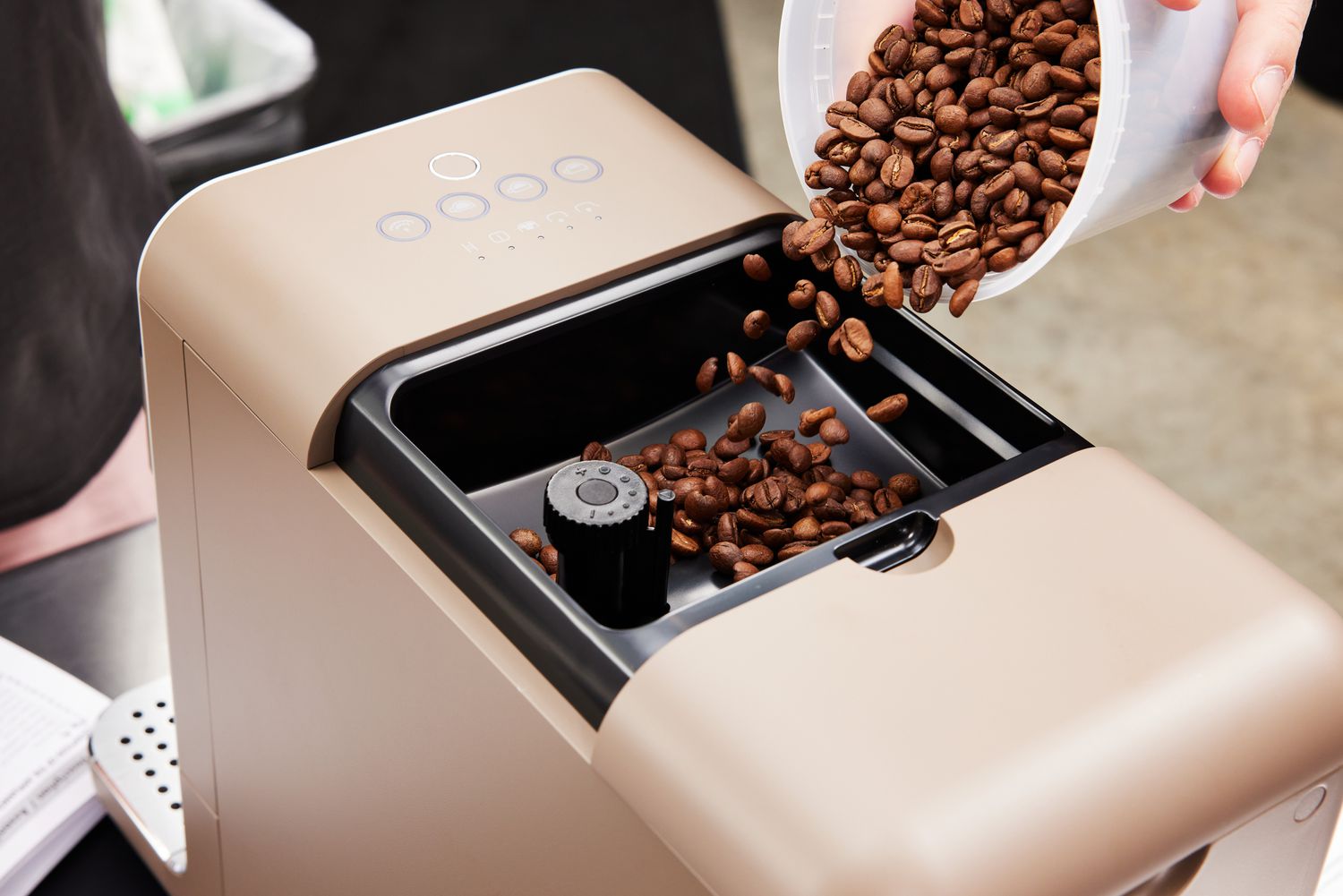 Coffee beans being poured into the SMEG Medium Fully-Automatic Coffee Machine's grinder.