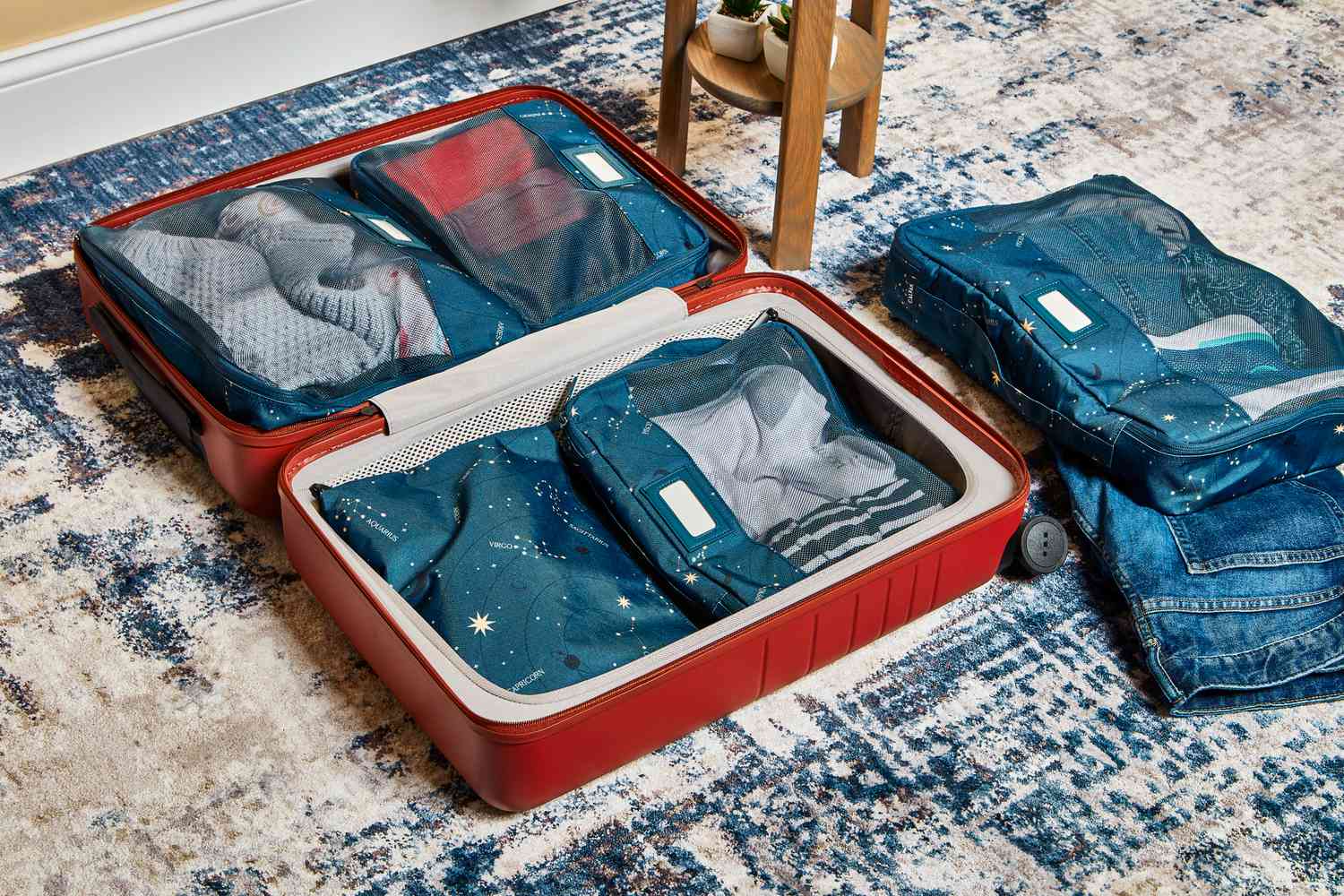 Calpak Packing Cubes 5-piece Set displayed in an open suitcase on a blue rug