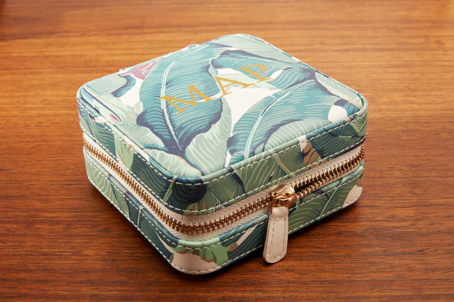 The Mark & Graham Small Travel Jewelry Case zipped close on a table. 