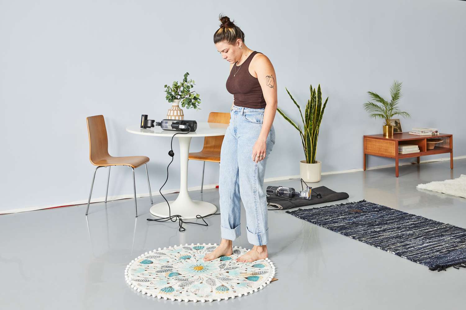 A person standing at the corner of the Uphome Pom Pom Round Floral Rug