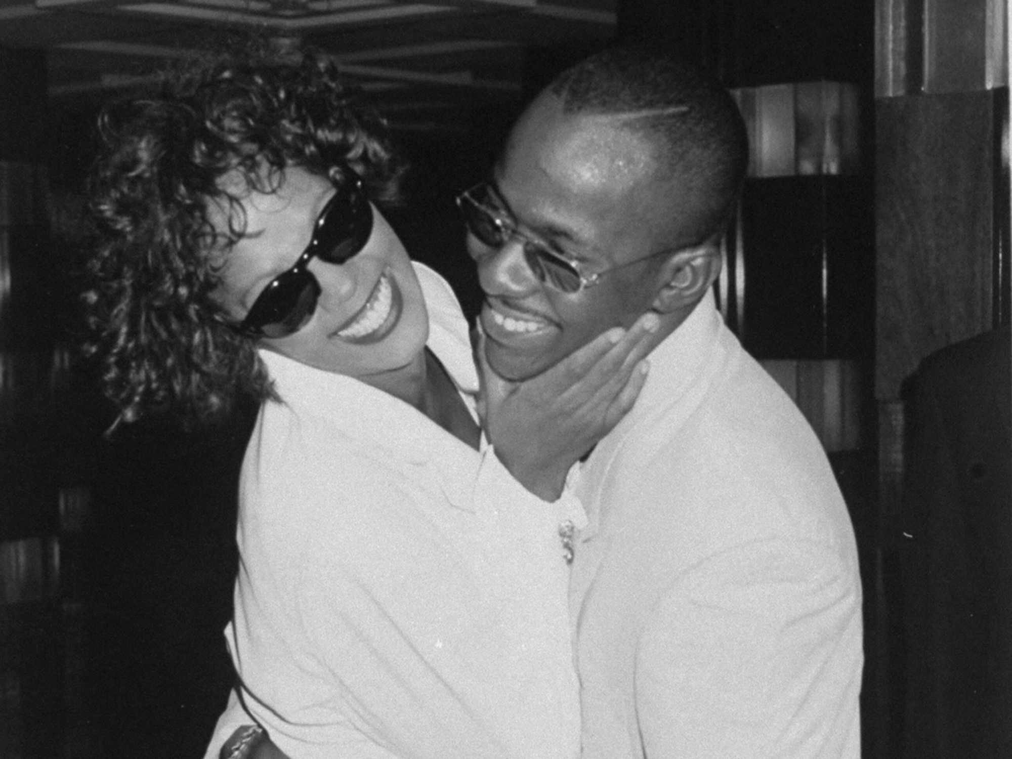 Whitney Houston and Bobby Brown wearing sunglasses and hugging after her concert