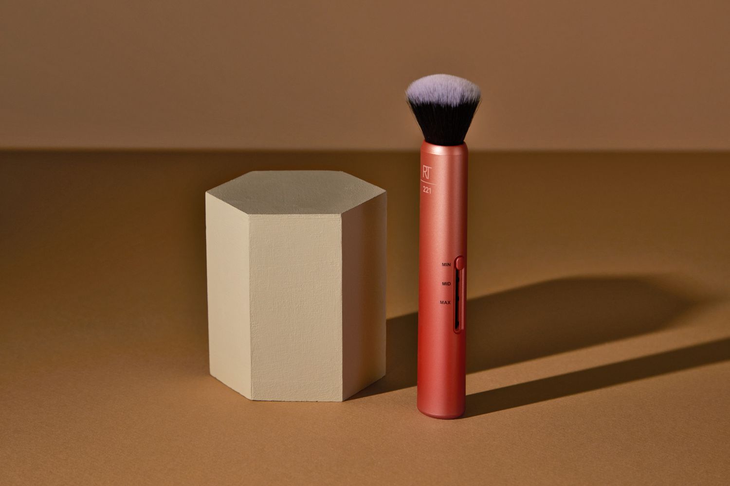 Real Techniques Custom Complexion Foundation 3-in-1 Brush standing upright next to a hexagon block