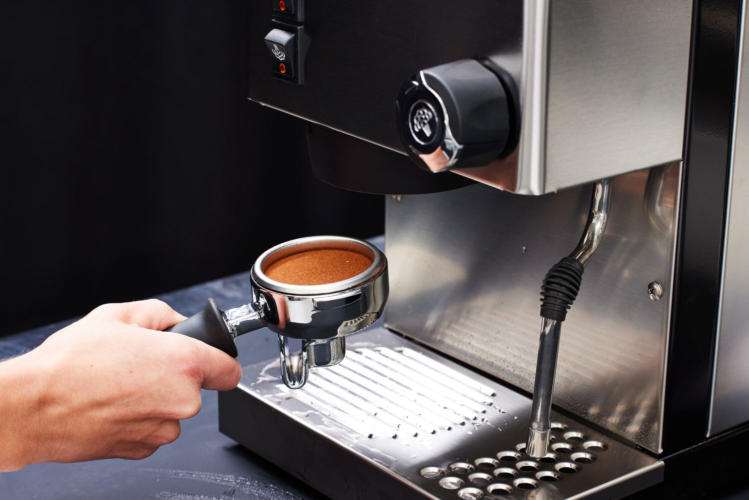A person holding the coffee ground filled portafilter of the Rancilio Silvia Espresso Machine.