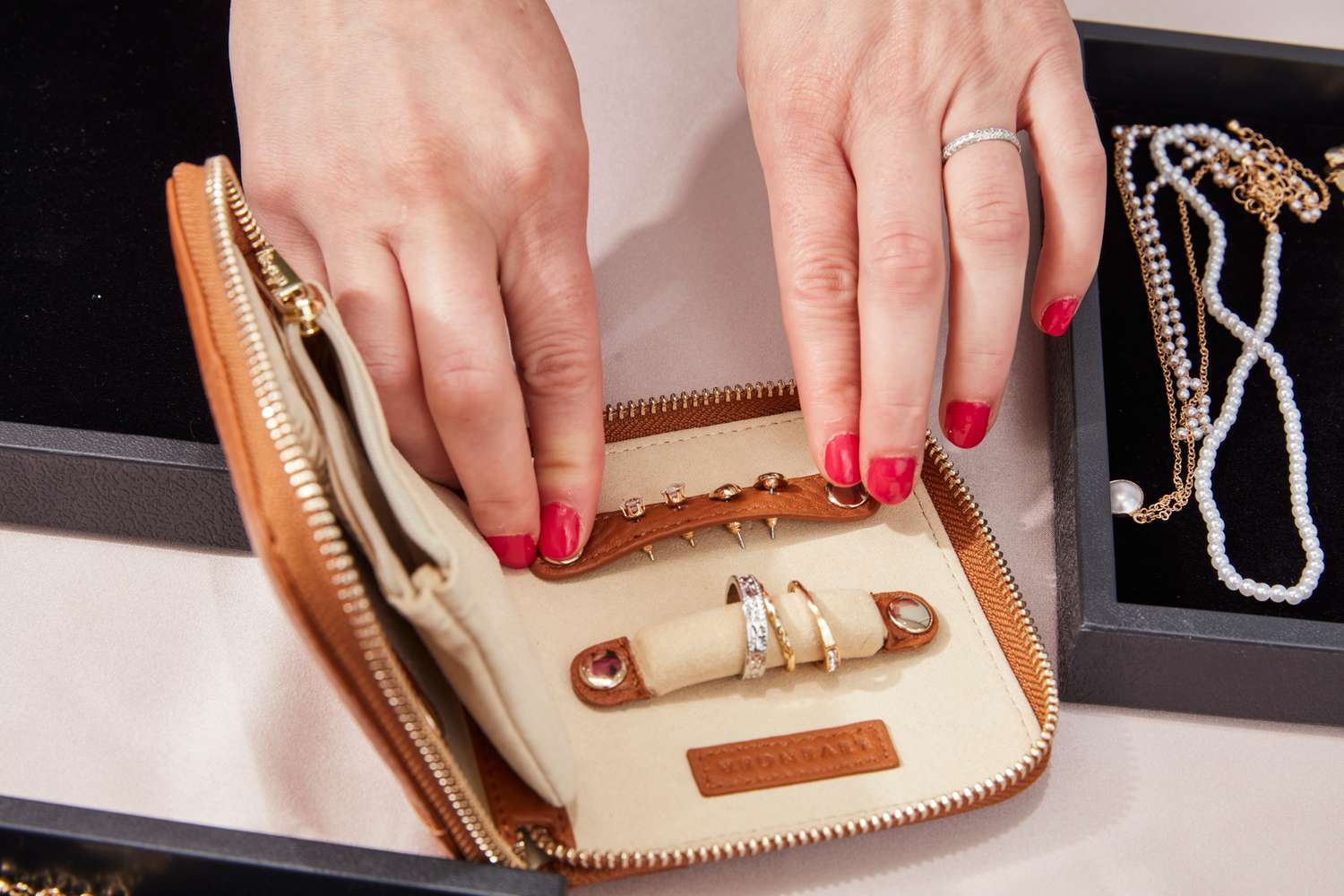 A person puts earrings into the Levenger Carrie Mini Jewelry Organizer.