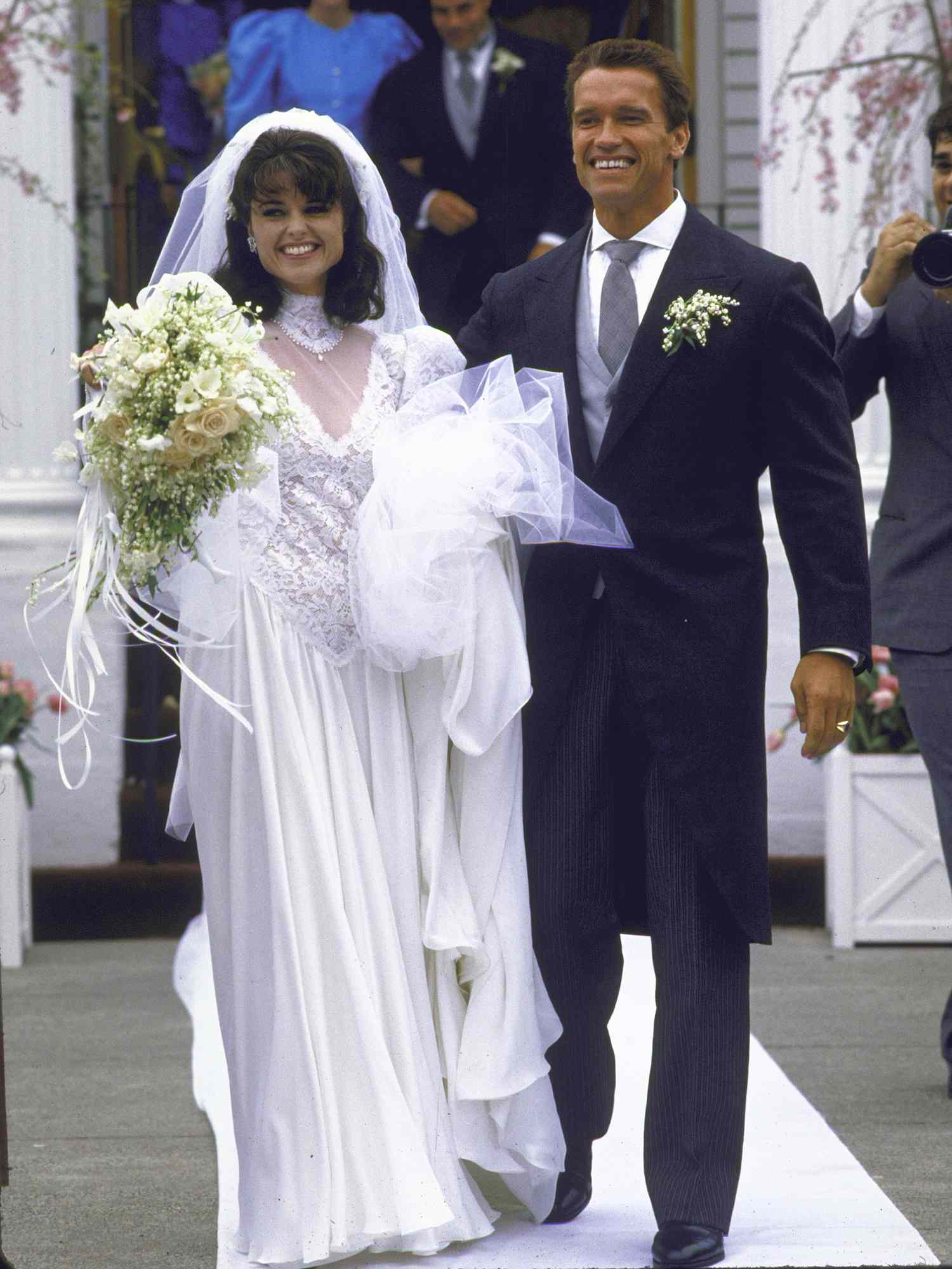 Arnold Schwarzenegger with his new wife Maria Shriver Schwarzenegger on their wedding day, standing in front of St. Francis Xaviers Church