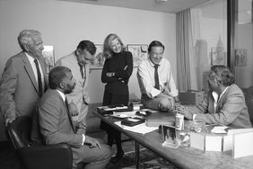 View of various members of the CBS '60 Minutes' news team in the office of producer Don Hewitt (right), New York, New York, 1986. Pictured are, from left, Harry Reasoner, Ed Bradley (seated), Morley Safer, Diane Sawyer, Mike Wallace, and Hewitt.