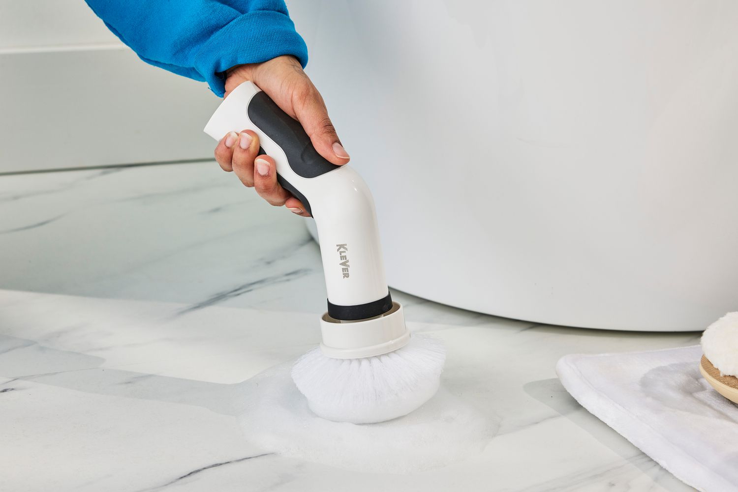 Close-up of a hand cleaning a marble floor with a Klever Electric Spin Scrubber with 8 Brushes