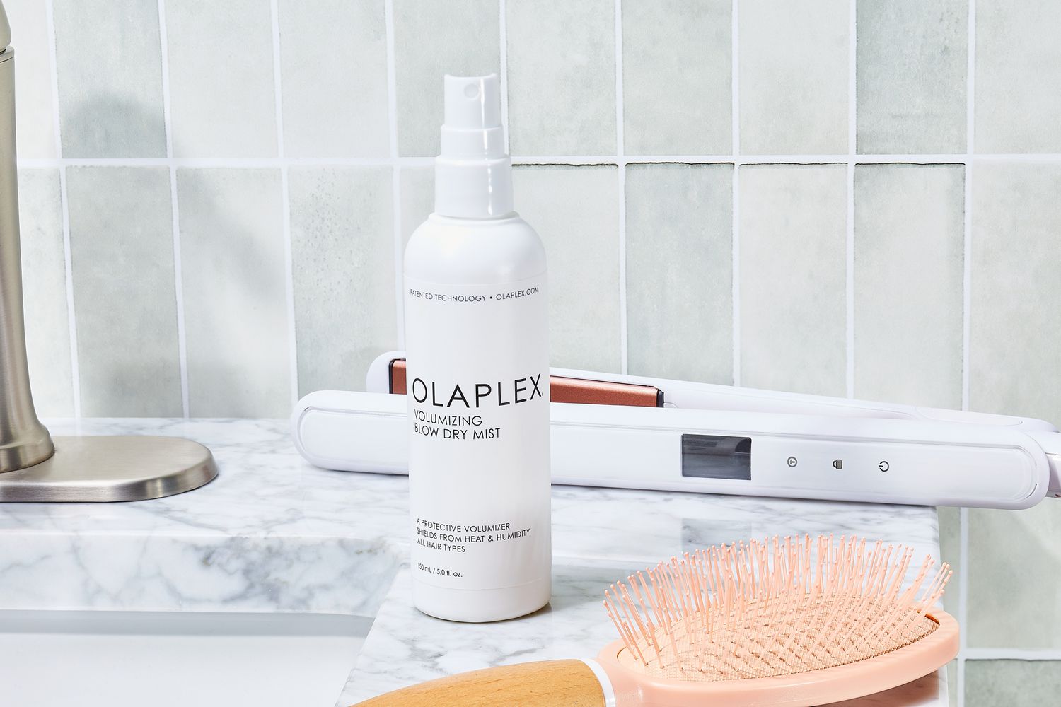 Oribe Balm DâOr Heat Styling Shield sits on bathroom counter with hair styling tools