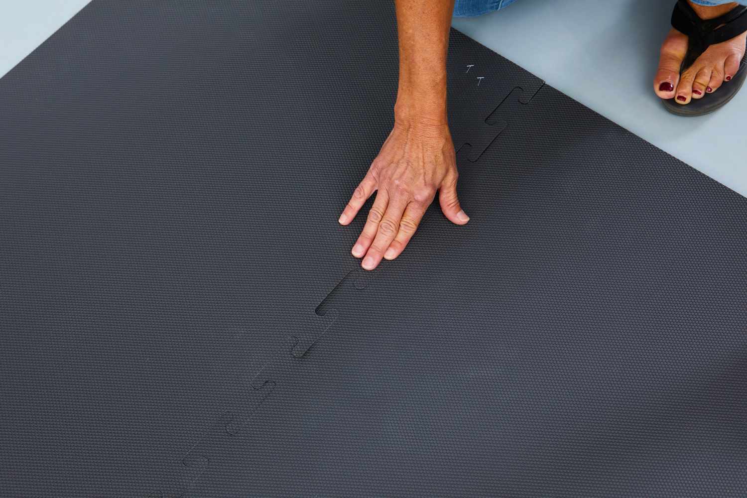 A person touching the Tumble Tabor Cushioned Rug Pad