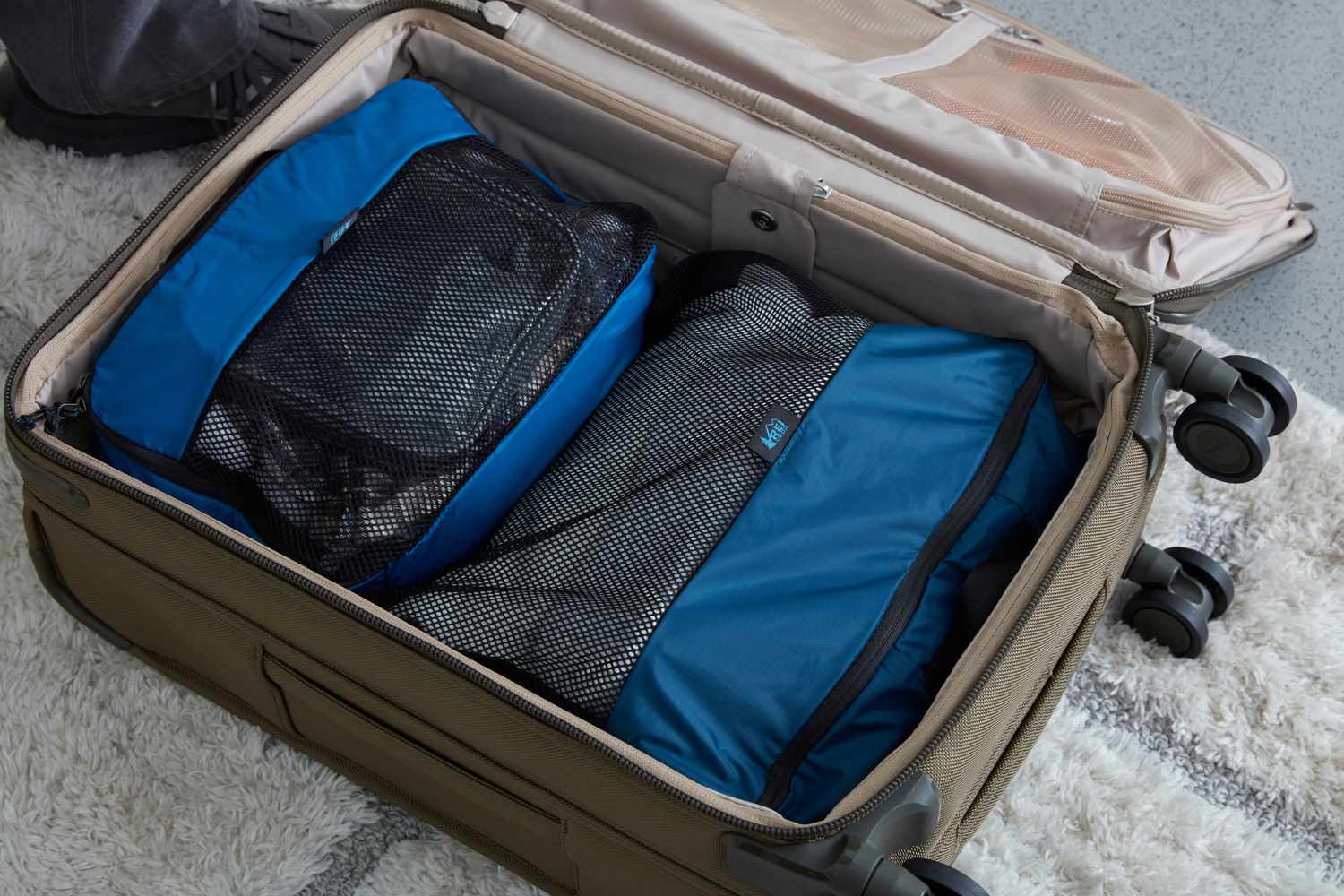 REI Co-op Expandable Packing Cube Set packed inside of a suitcase on rug