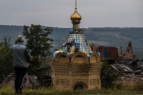 TOPSHOT - A woman stands in front of a destroyed church in Izium, Kramatorsk, eastern Ukraine, on September 11, 2022, amid the Russian invasion of Ukraine. - Ukraine said on Sptember 11, 2022, that its forces were pushing back Russia's military from strategic holdouts in the east of the country after Moscow announced a retreat from Kyiv's sweeping counter-offensive. (Photo by Juan BARRETO / AFP) (Photo by JUAN BARRETO/AFP via Getty Images)
