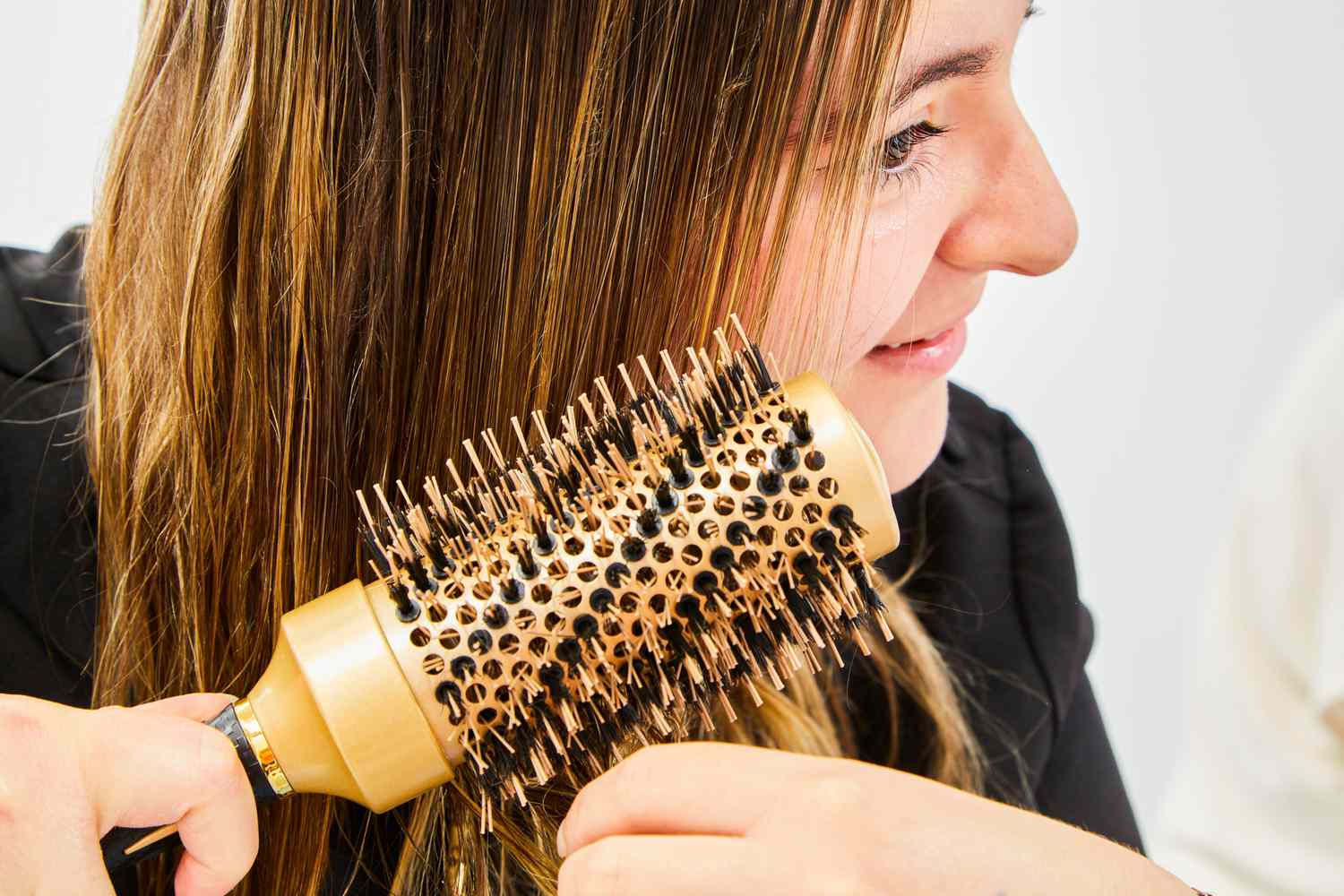 person brushes hair after using Oribe Balm DâOr Heat Styling Shield