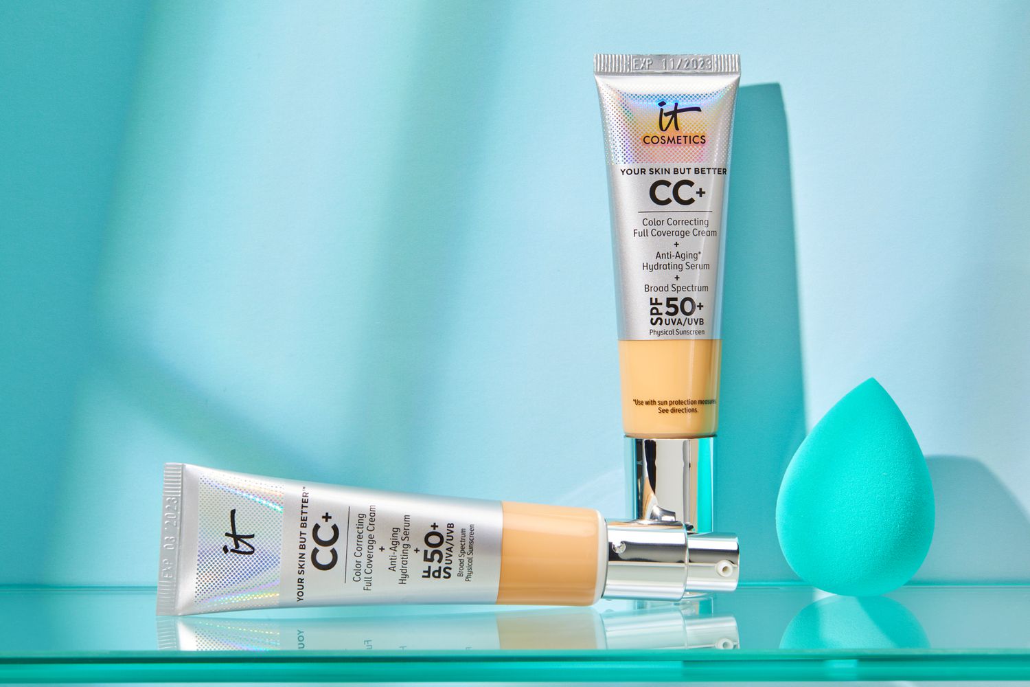 two tubes of IT Cosmetics CC+ Cream With SPF 50+ displayed in front of teal wall