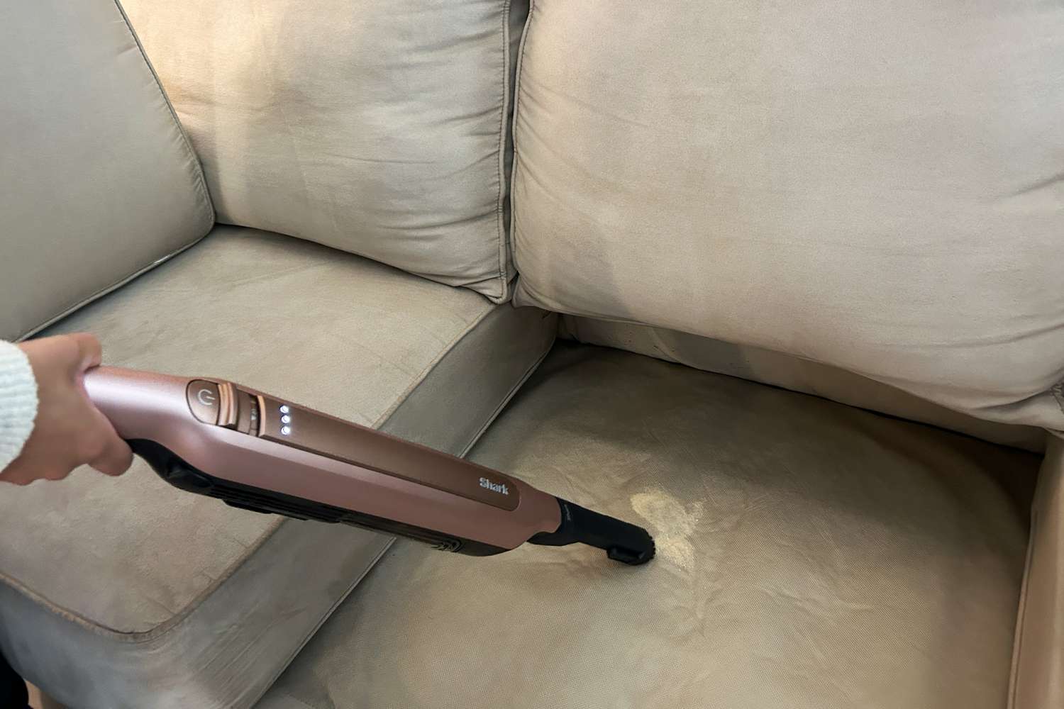 A person cleans a couch using the Shark Wandvac (without self-empty feature)