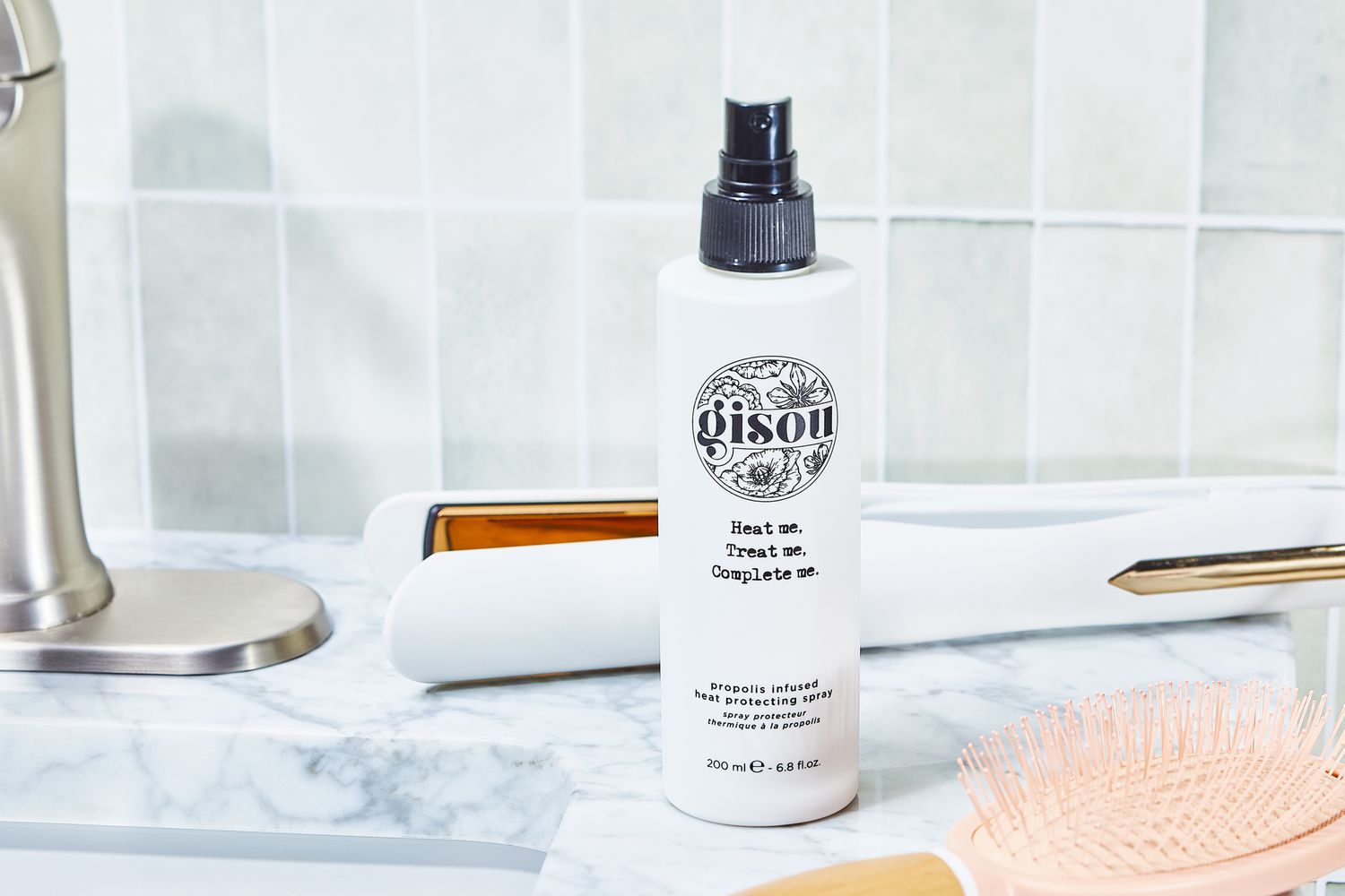 Gisou Heat Protecting Spray sits on bathroom counter next to hair styling tools