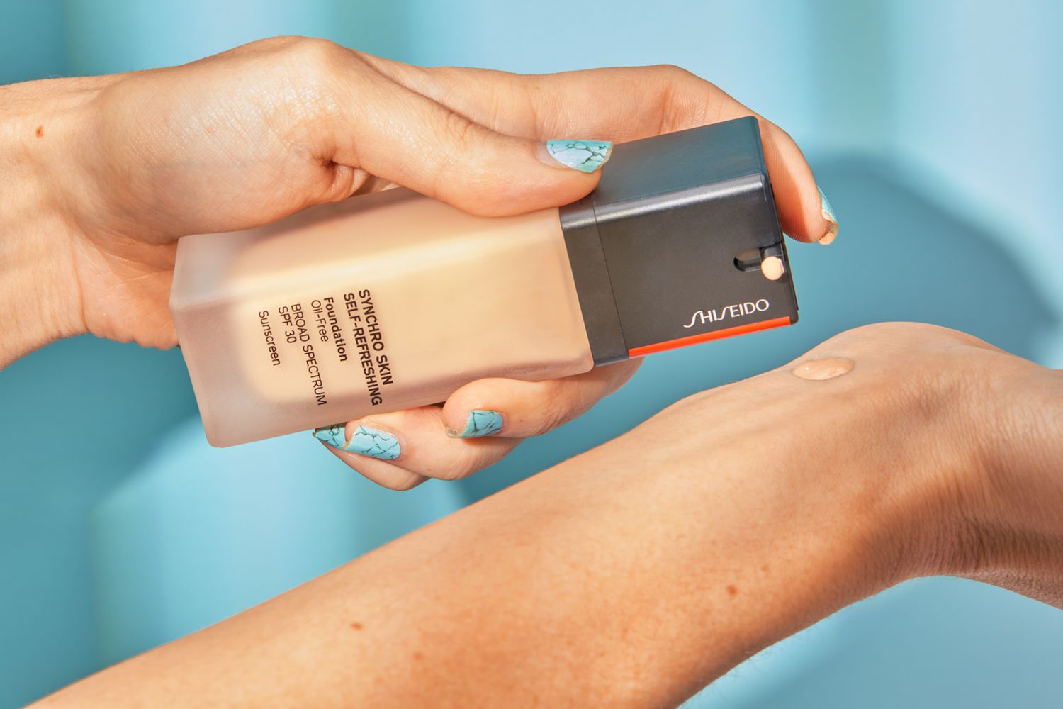 hand dispenses Shiseido Synchro Skin Self-Refreshing Foundation onto wrist