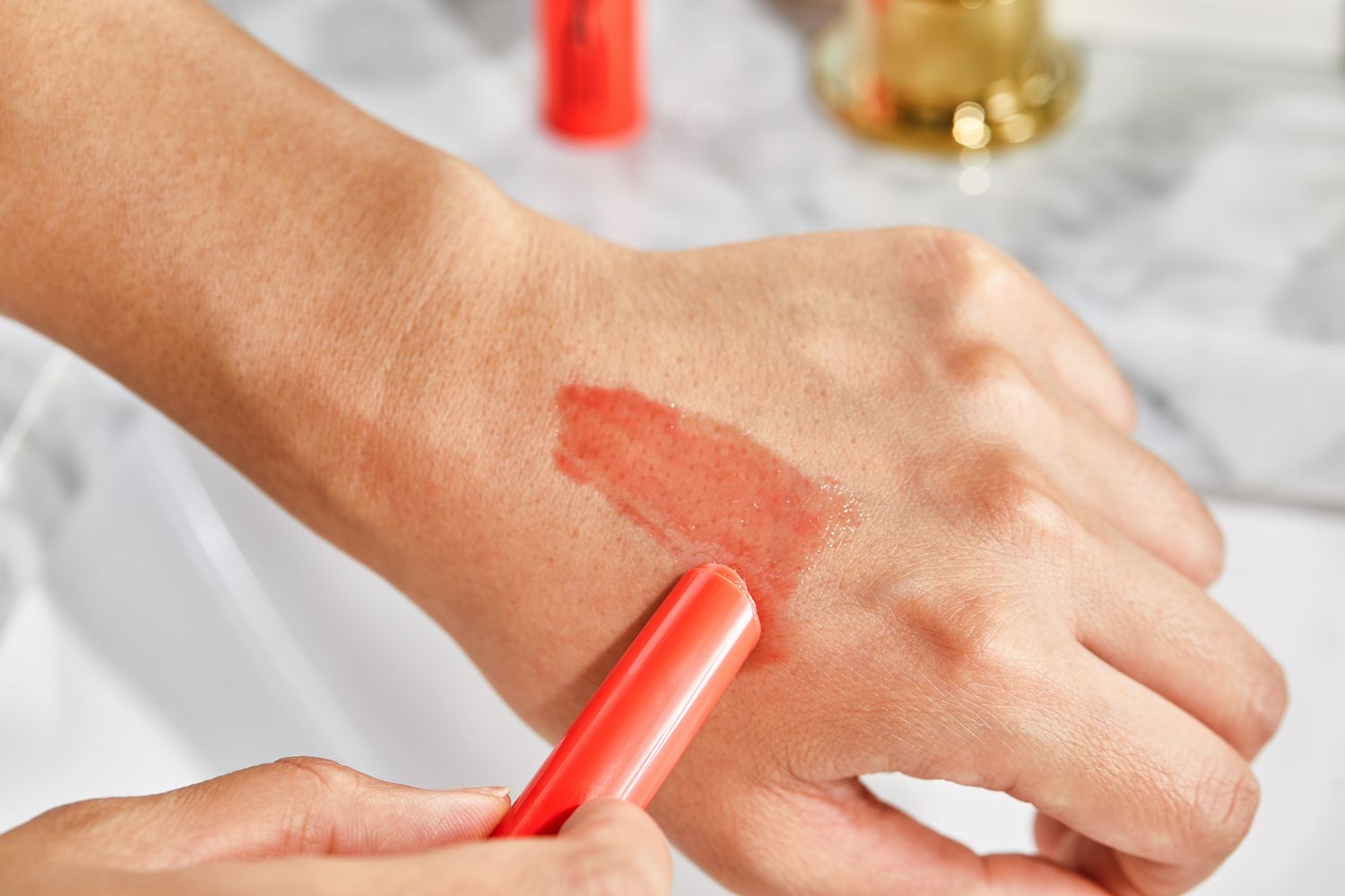 A person applying MAC Squirt Plumping Gloss Sticks to the back of their hand