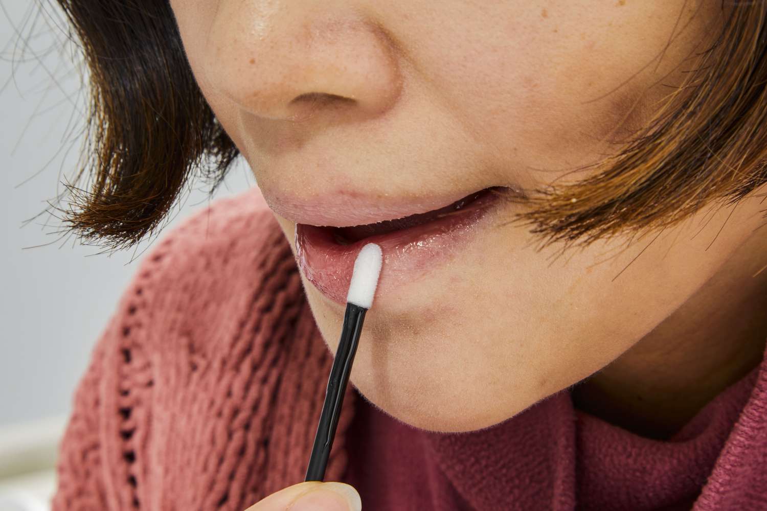 Woman applying Sunnie Skin Plump It Lips Hyaluronic + SPF 30 Lip Plumper to lips with applicatier