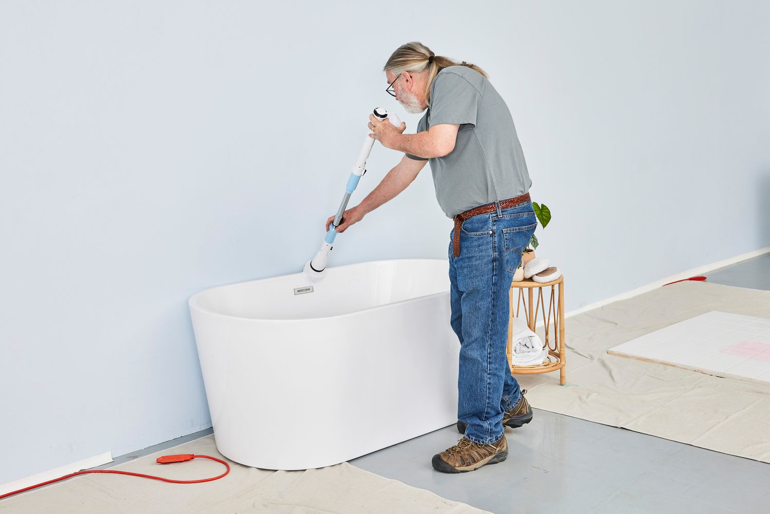 Person cleans a white tub with a TASVAC Electric Spin Scrubber
