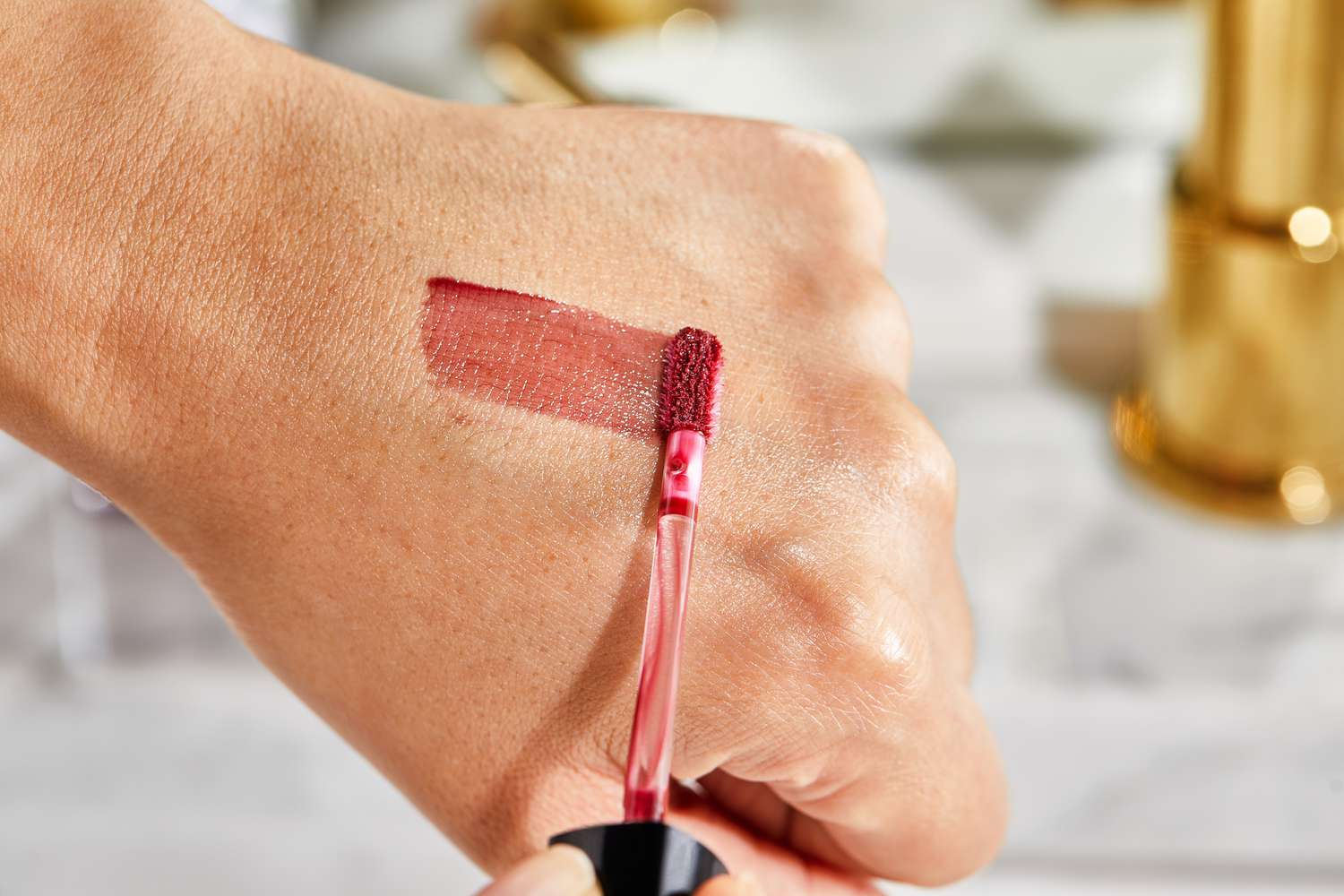 Close up of a person swiping Bobbi Brown Crushed Oil-Infused Gloss on the back of thier hand