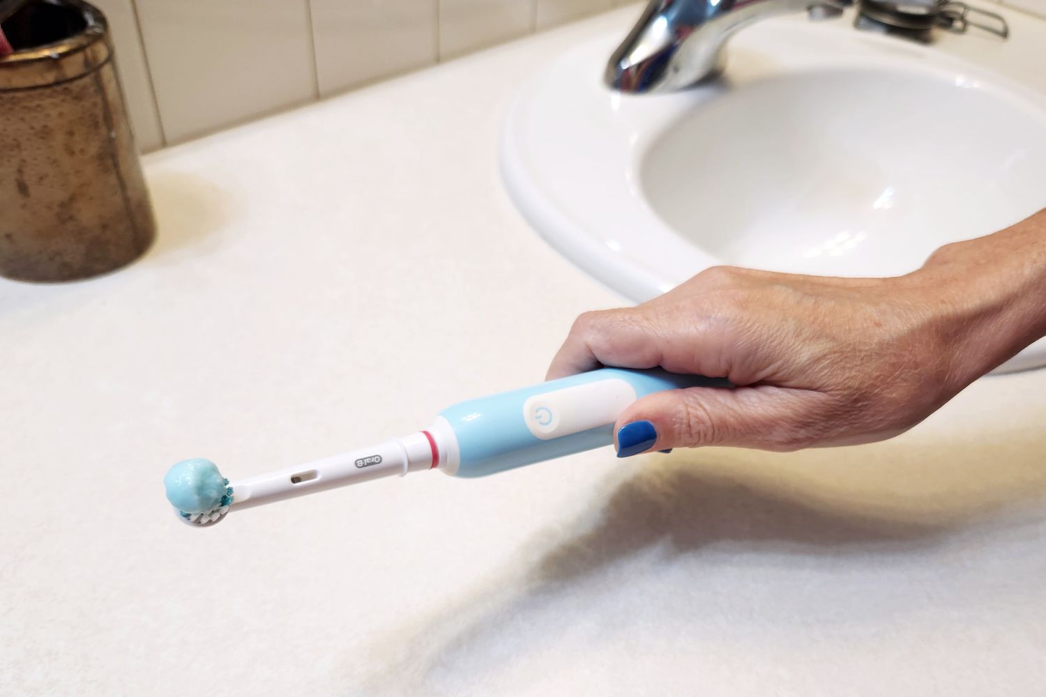 A hand holding a toothbrush containing Crest Pro-Health Clean Mint Toothpaste on the bristles