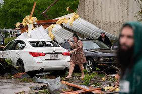 Robin Marquez, project coordinator for E.C.O. Builders, walks past her son's heavily damaged car after they sheltered in place inside the business, for what she said was a tornado, in the aftermath of severe storms that swept through the region in Slidell, La., Wednesday, April 10, 2024.