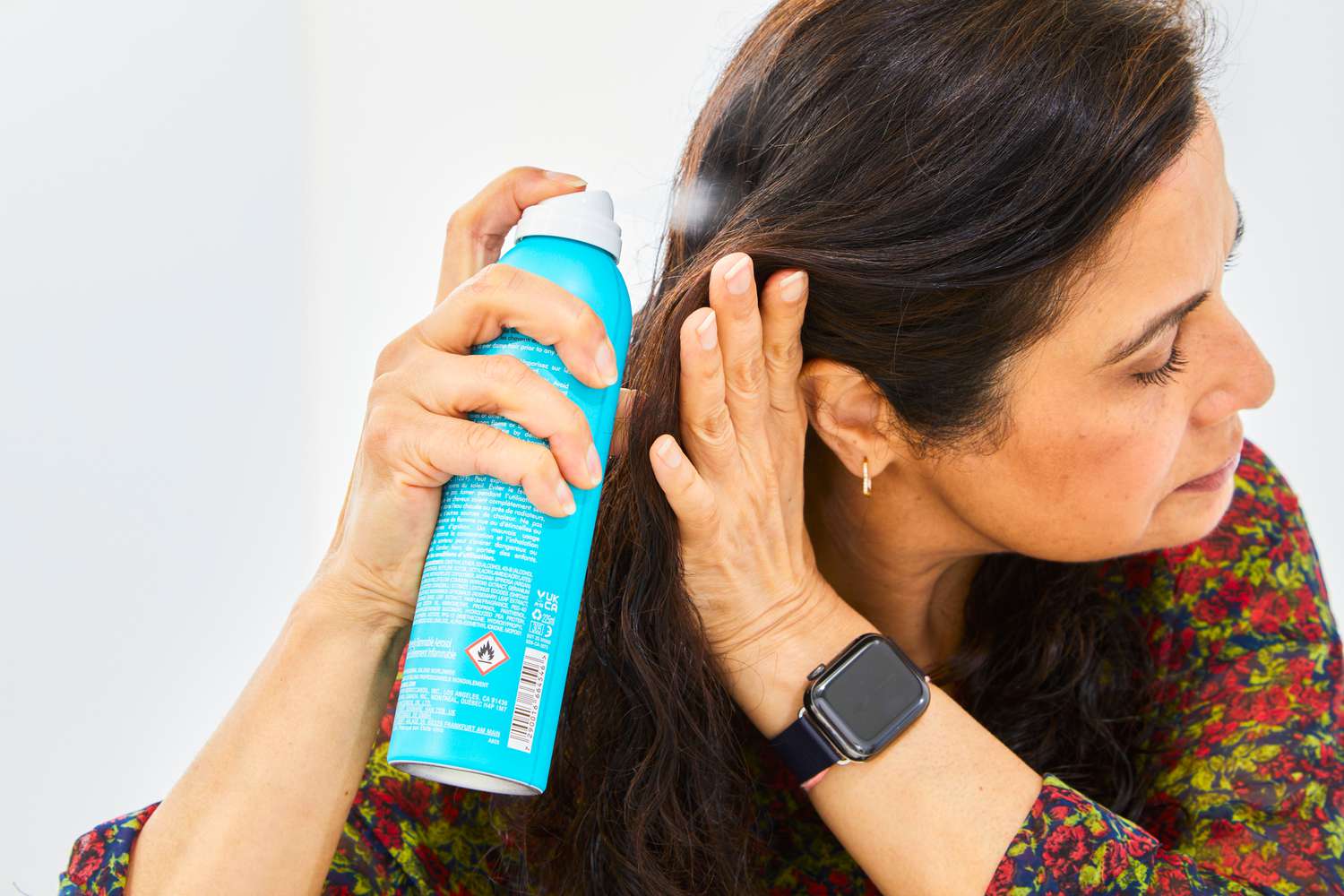 person sprays Moroccanoil Perfect Defense Heat Protectant in hair
