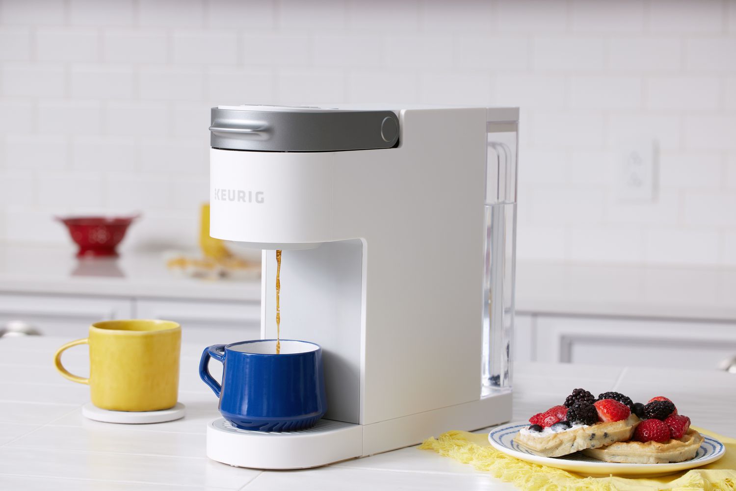 Keurig K-Slim Single Serve Coffee Maker pouring coffee into a cup next to a plate of pancakes