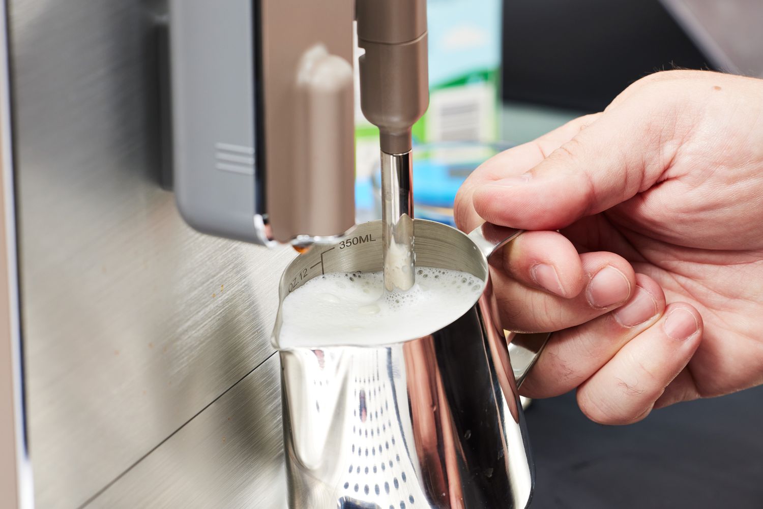 A person foaming milk using the SMEG Medium Fully-Automatic Coffee Machine.
