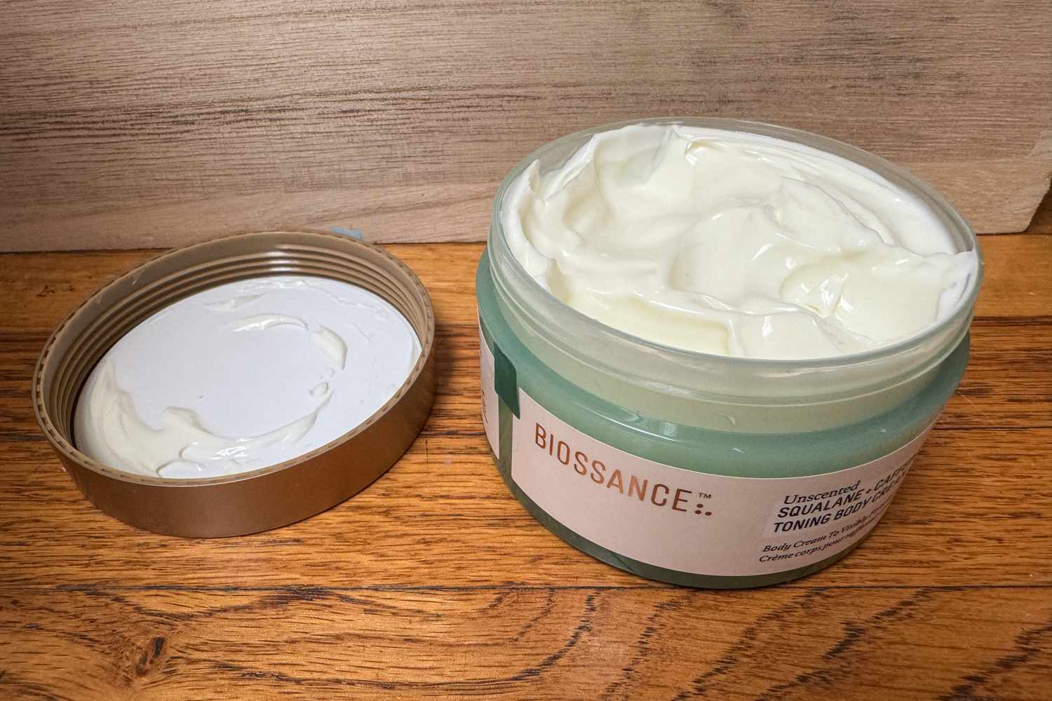A jar of Biossance Squalane + Caffeine Toning Body Cream with the cap off