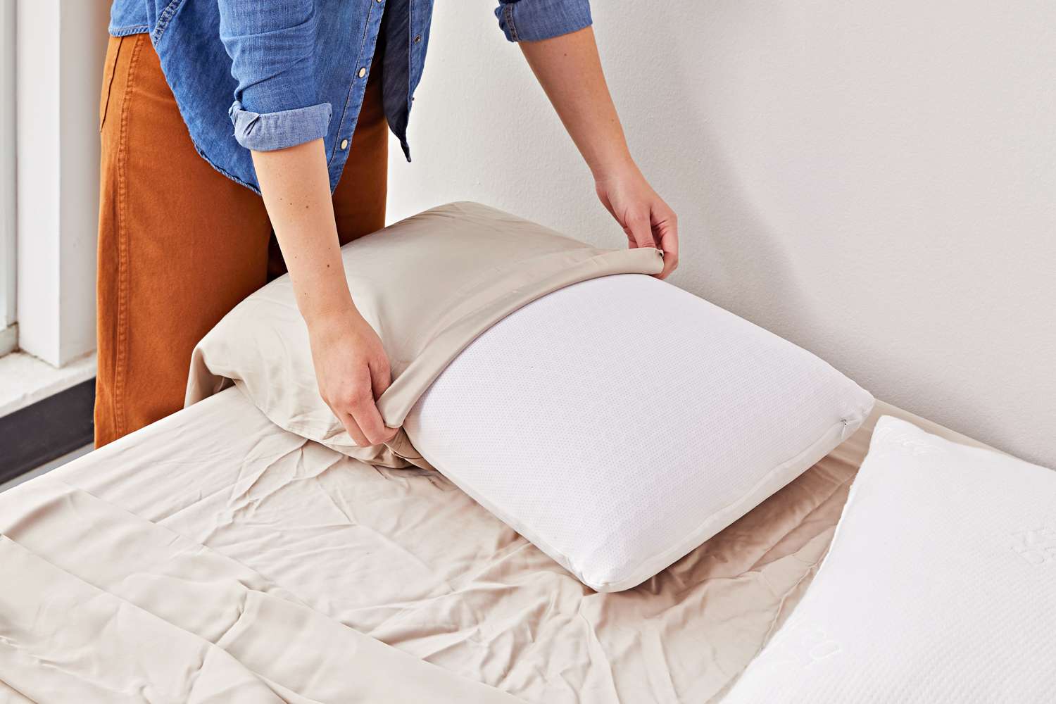 A person covering a pillow in a Cozy Earth Bamboo Sheet Set pillowcase