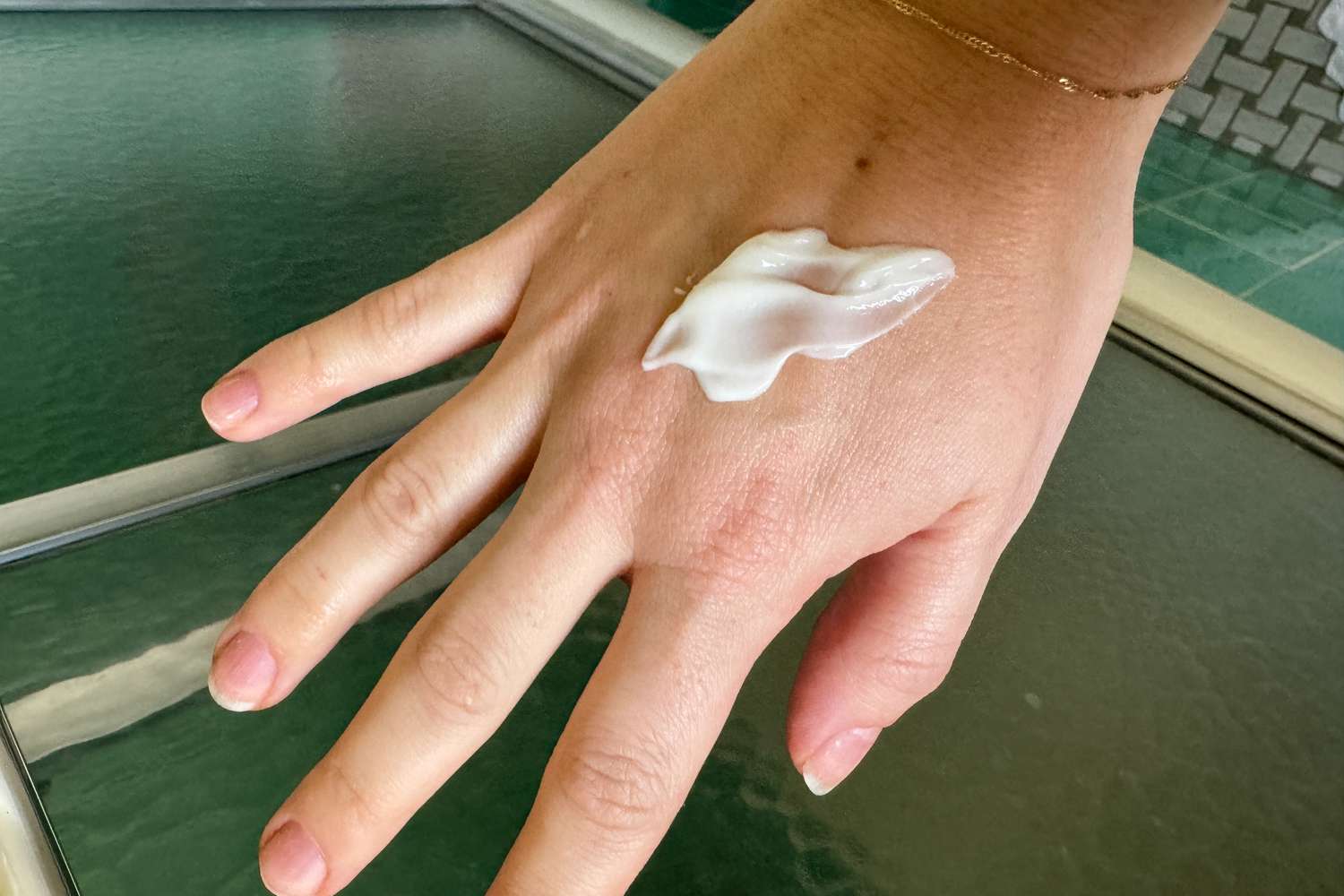 A hand with Biossance Squalane + Caffeine Toning Body Cream on it