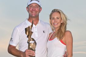 Lucas Glover holds the trophy with his wife, Krista Glover, on the 18th green after the final round of the FedEx St. Jude Championship at TPC Southwind on August 13, 2023