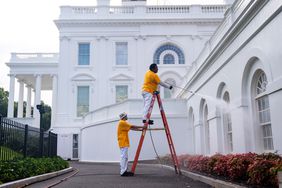 Maintenance workers power wash the exterior of the White House