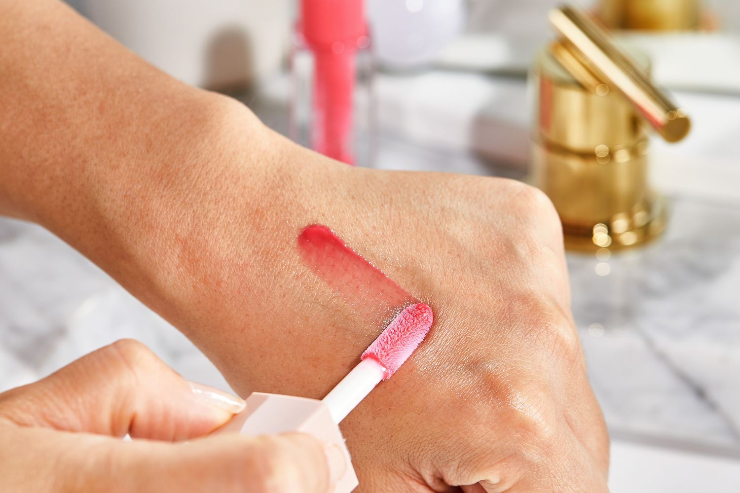 Close up of a person swiping Maybelline Lifter Gloss with Hyaluronic Acid on the back of their hand