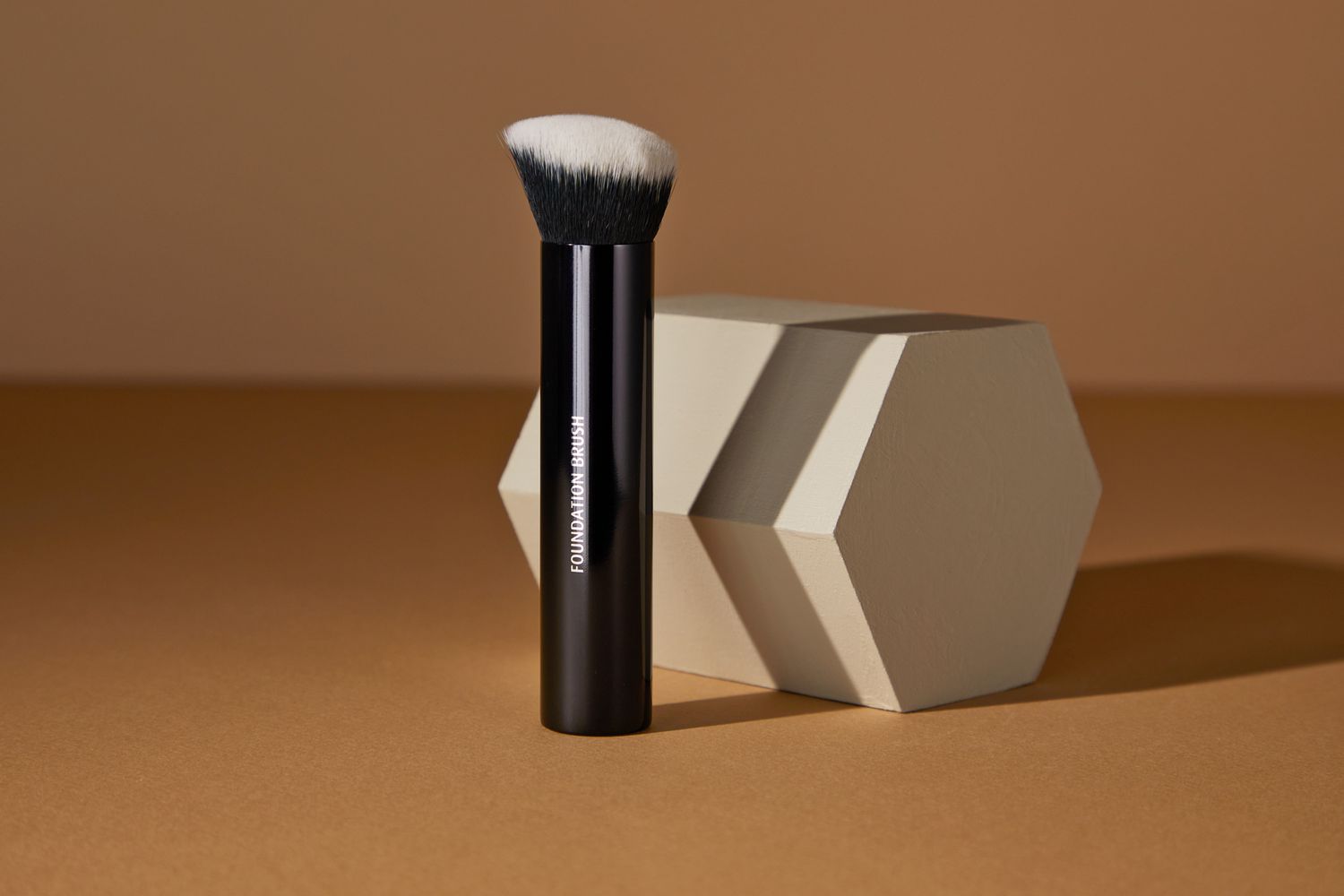 Lune+Aster Foundation Brush standing upright next to a hexagon block