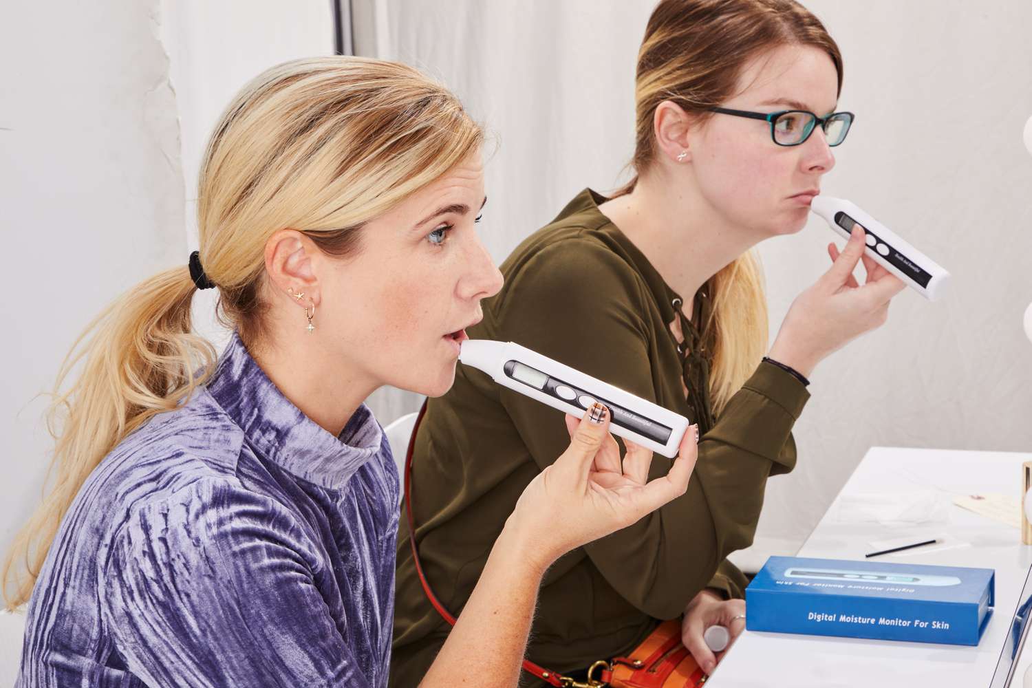 Two people using digital moisture monitors for skin on their lips